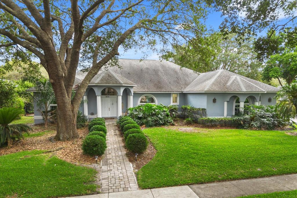 A single-story gray house with a brick walkway and a large tree in the yard — 8050 RURAL RETREAT COURT, ORLANDO, FL