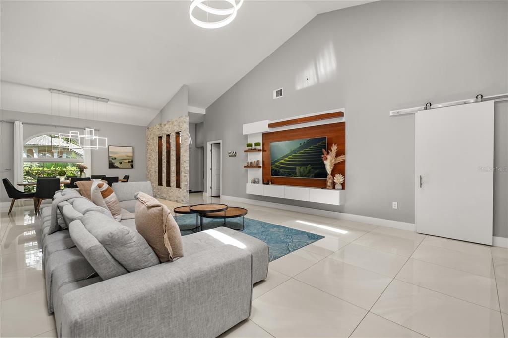 A living room features a large sectional sofa, a wall-mounted television, and tile flooring — 8050 RURAL RETREAT COURT, ORLANDO, FL