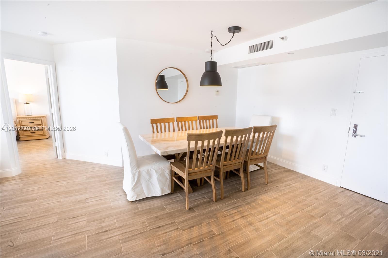 A dining room features a marble-topped table, wooden chairs, and a black pendant light — AVENTURA, FL