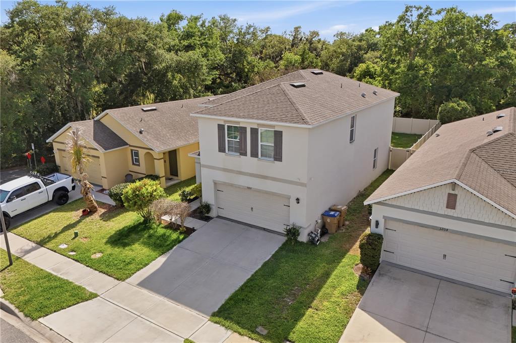 An elevated view shows a two-story beige house situated between two single-story homes — 3202 SURFBIRD STREET, KISSIMMEE, FL