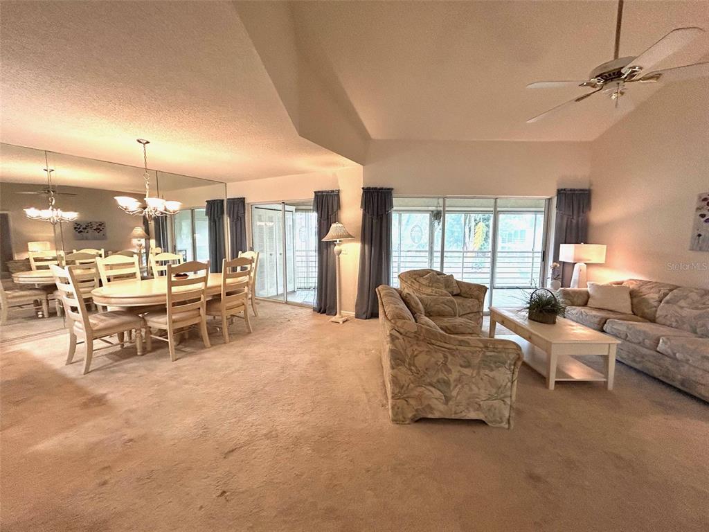 A living room features floral-patterned furniture, a white coffee table, and large sliding glass doors — 6101 34TH STREET W UNIT 22H, BRADENTON, FL