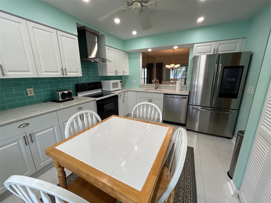 A kitchen features white cabinets, stainless steel appliances, light countertops, and light blue walls — 6101 34TH STREET W UNIT 22H, BRADENTON, FL