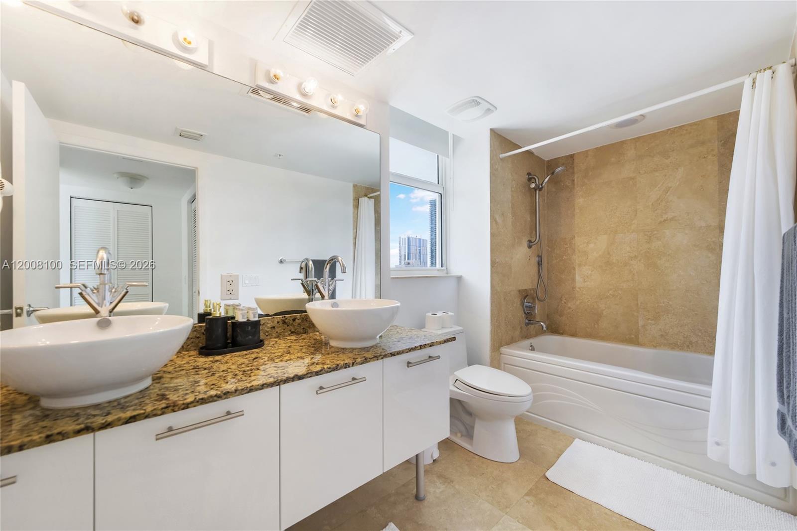 A bathroom features a double vanity with vessel sinks, granite countertops, and a shower-tub combo — 41 SE 5th St # 504, Miami FL 33131, MIAMI, FL