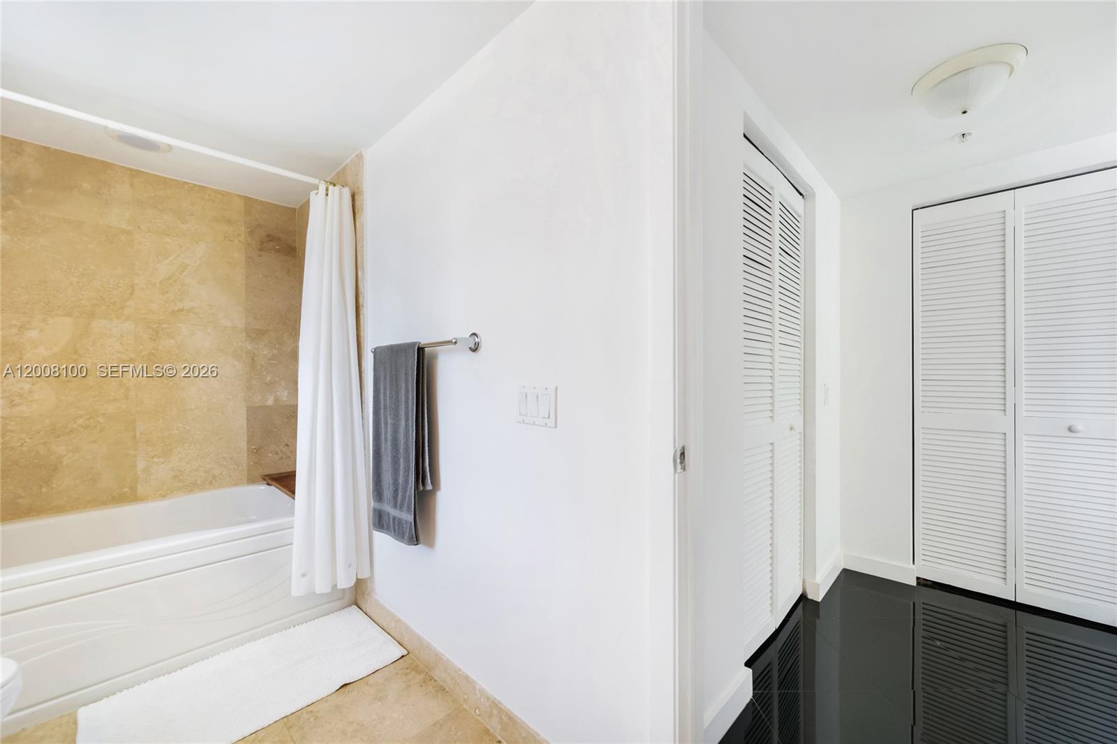 A bathroom features a tiled tub area, a white towel, and white louvered closet doors — 41 SE 5th St # 504, Miami FL 33131, MIAMI, FL