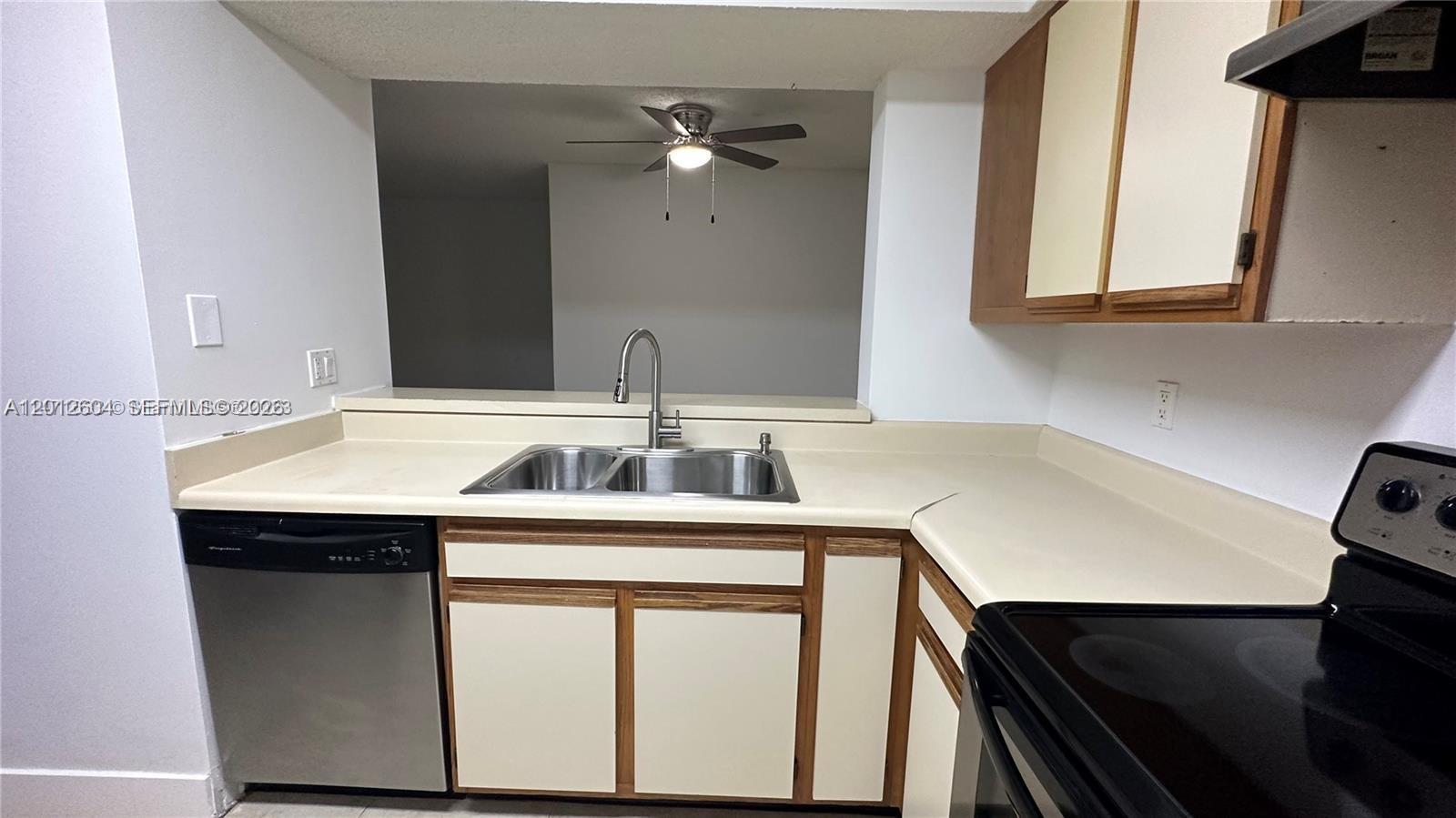 A kitchen features a stainless steel dishwasher, a double sink, and light-colored laminate countertops — 1243 SW 46th Ave # 1111, Pompano Beach FL 33069, POMPANO BEACH, FL