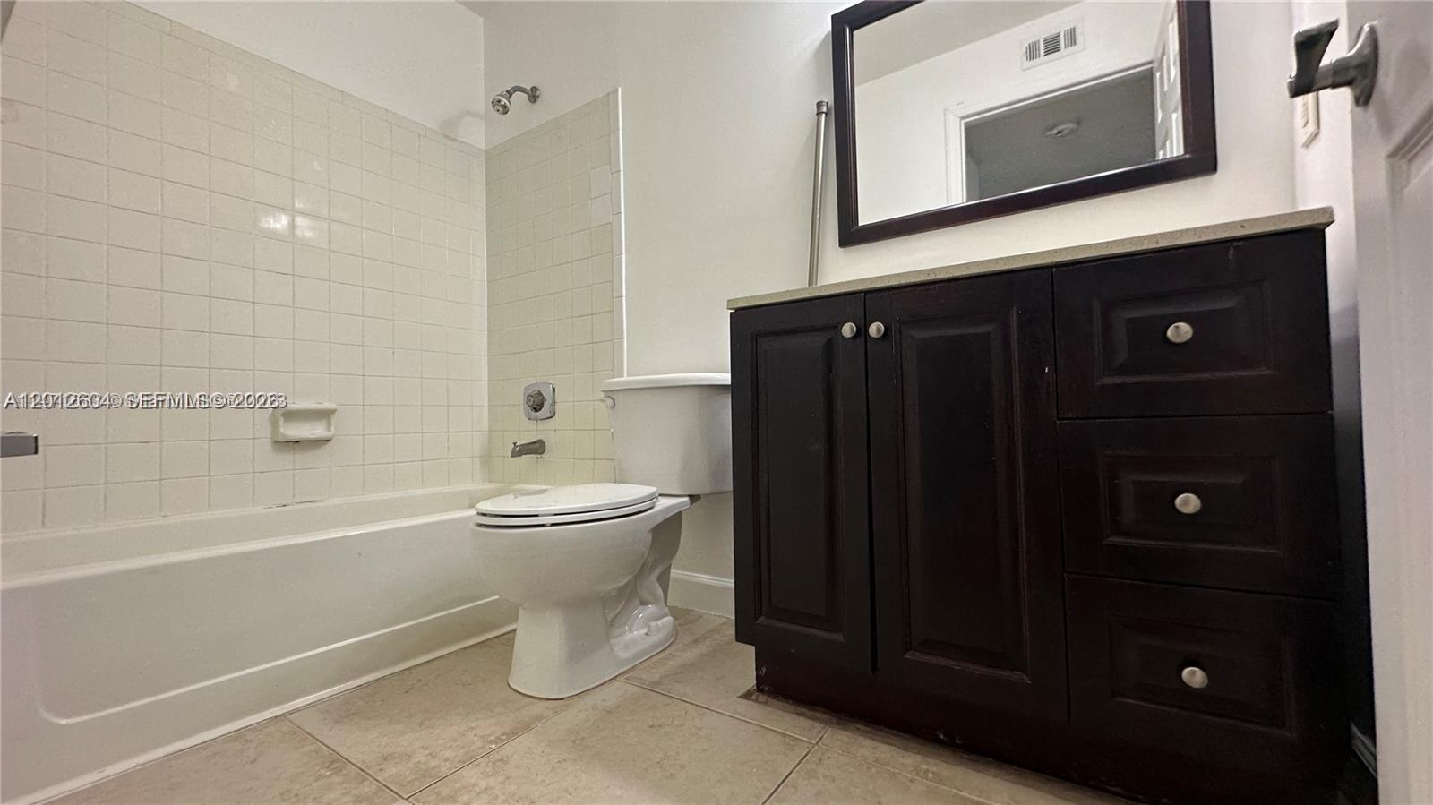 A bathroom features a white bathtub, a toilet, and a dark wood vanity cabinet — 1243 SW 46th Ave # 1111, Pompano Beach FL 33069, POMPANO BEACH, FL