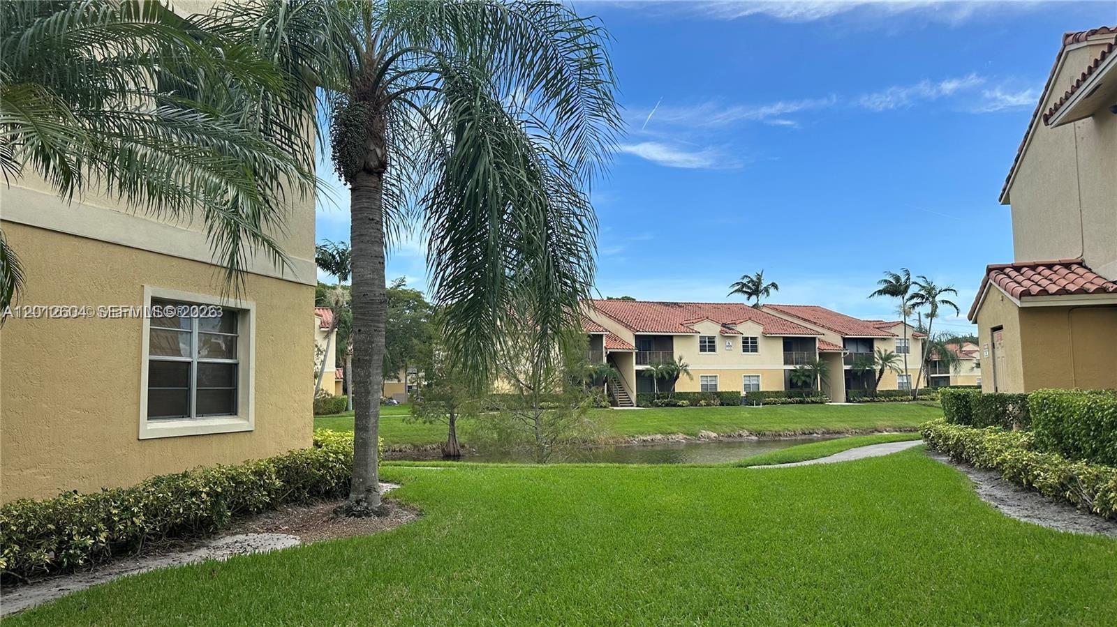A view of apartment buildings with yellow stucco walls and red tile roofs near water — 1243 SW 46th Ave # 1111, Pompano Beach FL 33069, POMPANO BEACH, FL