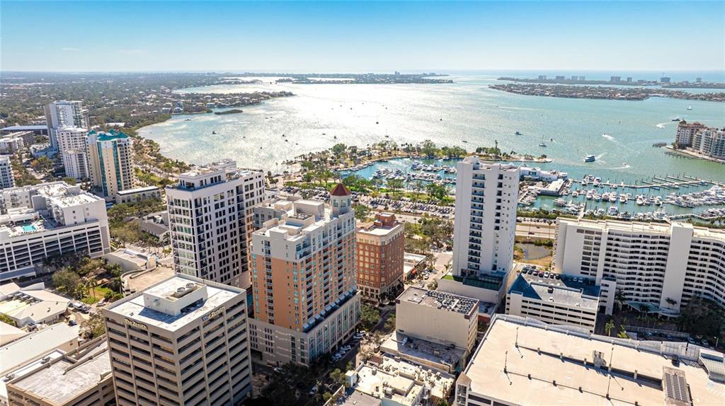 An aerial view shows a coastal city with high-rise buildings, a marina, and a large bay — 1350 MAIN STREET UNIT 1501, SARASOTA, FL