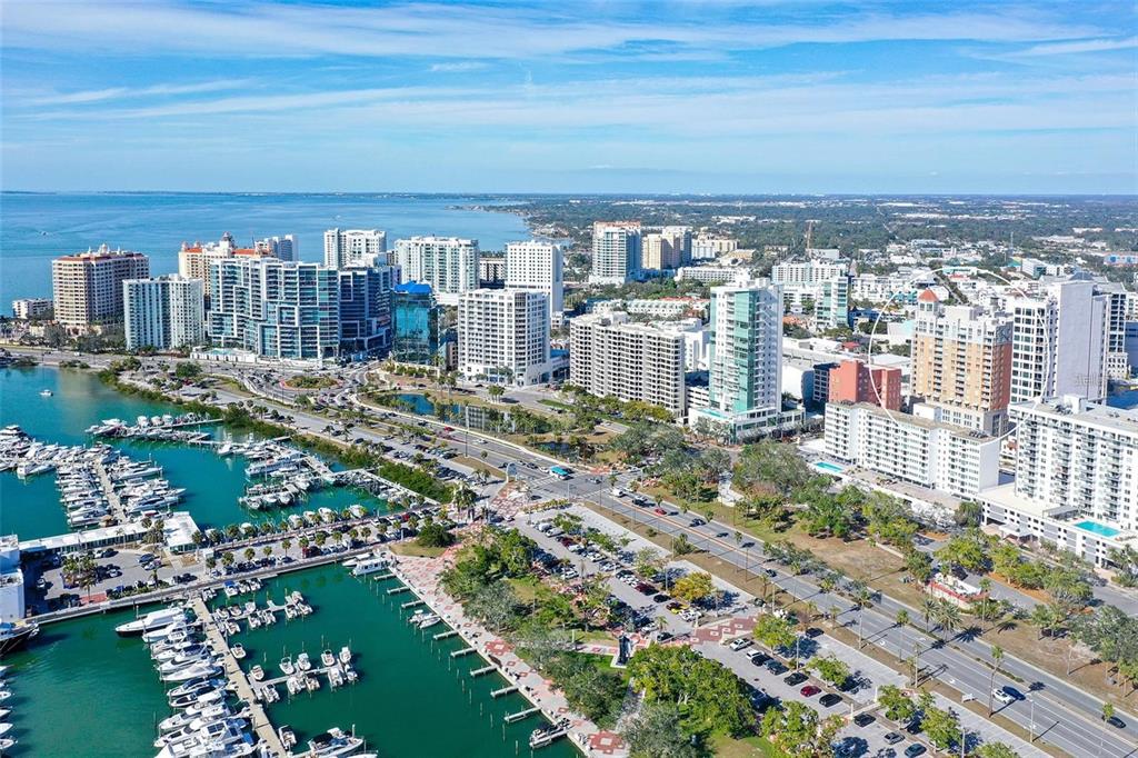 An aerial view shows a coastal city with a marina, high-rise buildings, and roads — 1350 MAIN STREET UNIT 1501, SARASOTA, FL