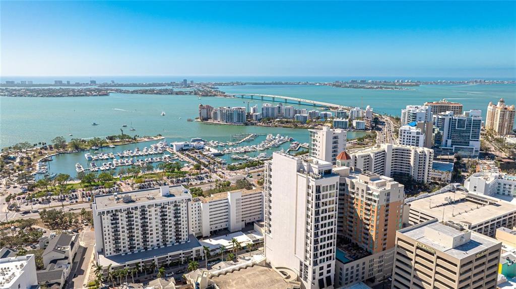 An aerial view of a coastal city featuring high-rise buildings, a marina, and a bridge — 1350 MAIN STREET UNIT 1501, SARASOTA, FL