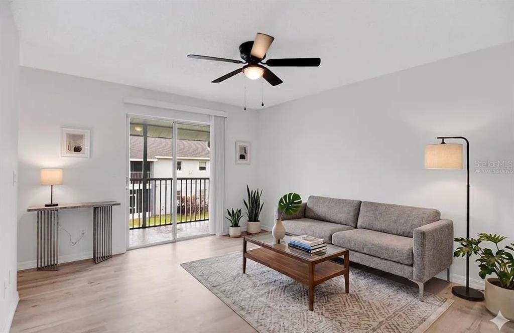 A living room with a gray sofa, coffee table, area rug, and sliding glass balcony doors — 4100 PERSHING POINTE PLACE UNIT 3, ORLANDO, FL