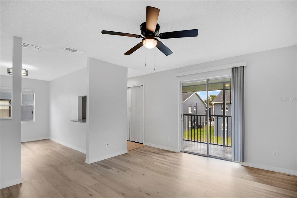 A living room with light wood flooring, a ceiling fan, and a sliding glass door — 4100 PERSHING POINTE PLACE UNIT 3, ORLANDO, FL