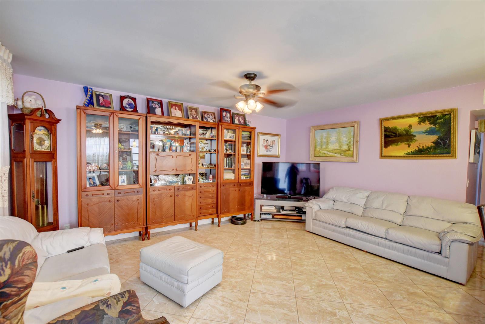 A living room features light purple walls, tile flooring, wooden cabinetry, and two white sofas — 138 Flanders C, Delray Beach FL 33484, DELRAY BEACH, FL