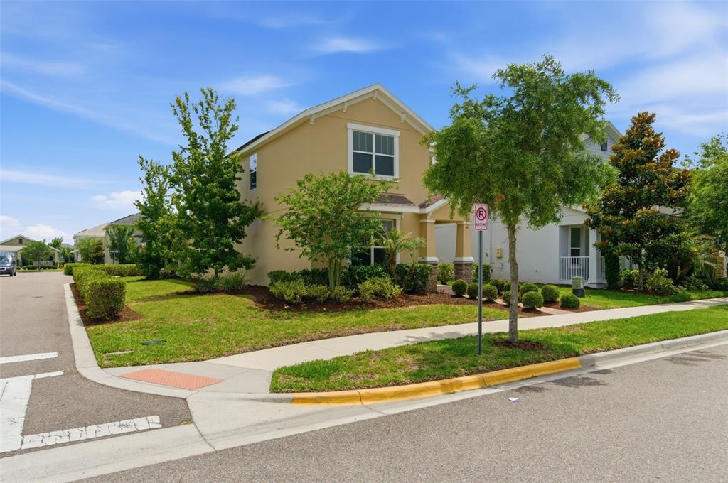 A two-story tan house with a green lawn sits on a corner lot — 11932 HOMETOWN PLACE, ORLANDO, FL
