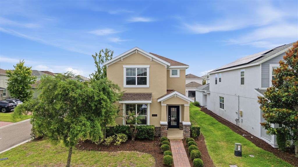 A two-story tan house with a brick walkway and a front-facing gable roof — 11932 HOMETOWN PLACE, ORLANDO, FL