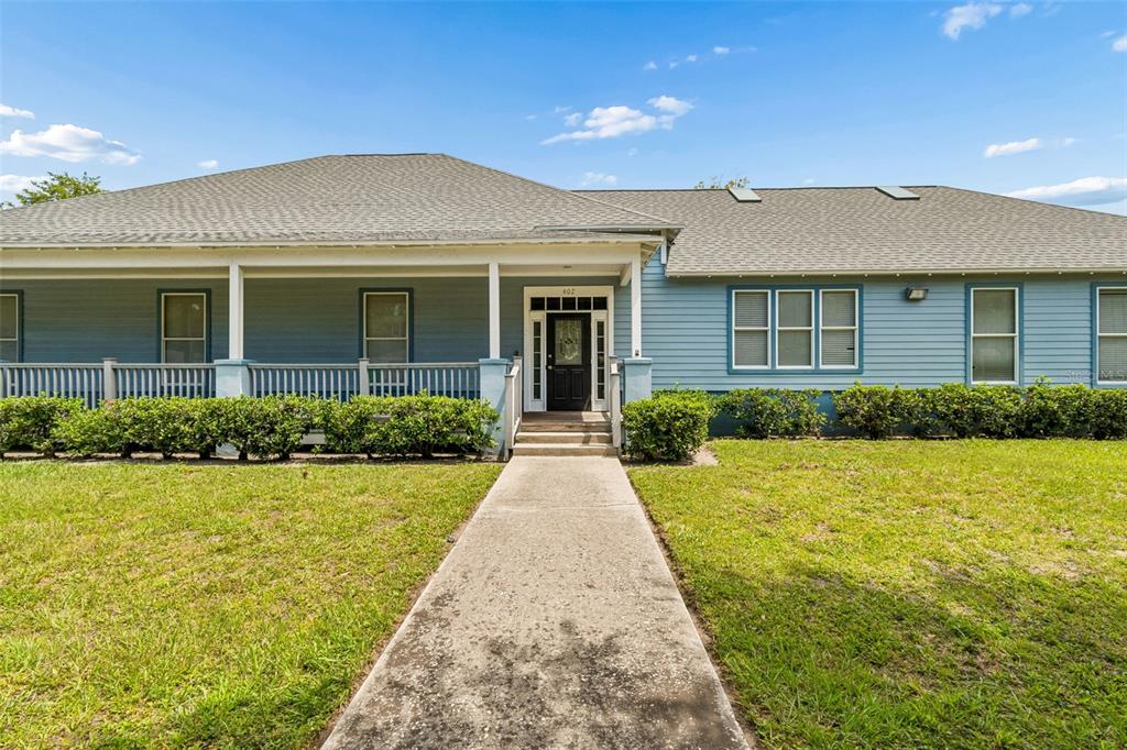 A blue single-story house with a front porch, walkway, and green lawn under a sky — 402 E 7TH AVENUE, TAMPA, FL