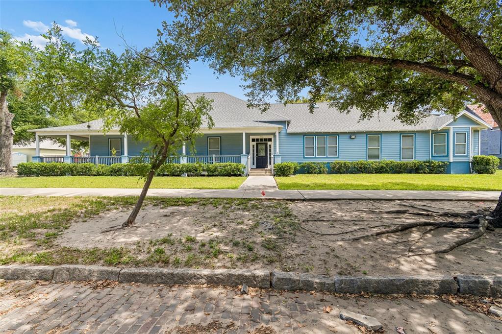 A blue single-story house with a wraparound porch sits behind a sidewalk and trees — 402 E 7TH AVENUE, TAMPA, FL