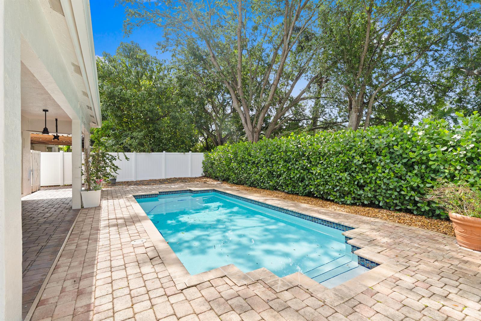 A rectangular swimming pool sits on a brick patio next to a tall green hedge — 19360 SW 29th Court, Miramar FL 33029, MIRAMAR, FL