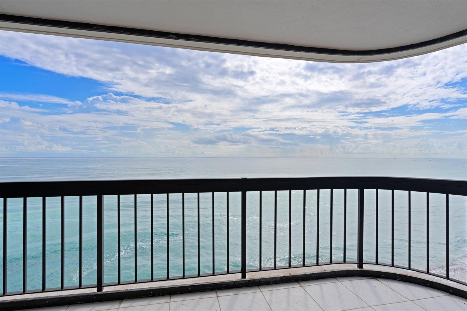 A balcony with a black metal railing overlooks the ocean under a cloudy blue sky — 5380 N Ocean Drive # 10d, Riviera Beach FL 33404, RIVIERA BEACH, FL