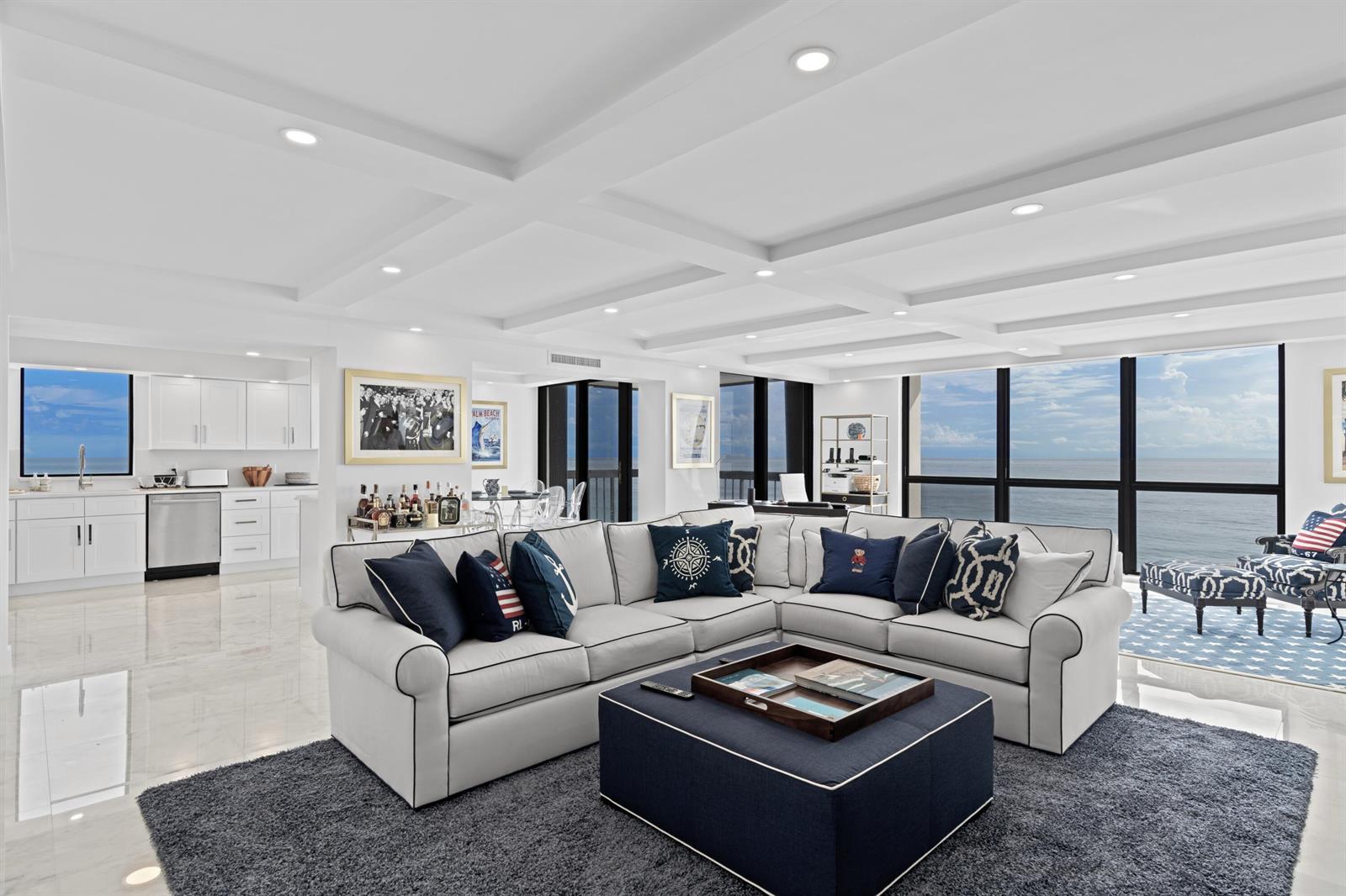 A bright living room features a large sectional sofa, coffered ceilings, and floor-to-ceiling ocean views — 5380 N Ocean Drive # 10d, Riviera Beach FL 33404, RIVIERA BEACH, FL