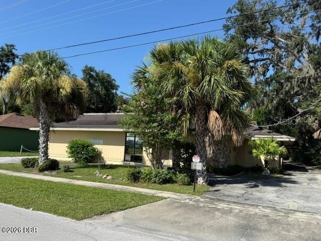 A single-story building with yellow siding and palm trees stands beside a paved driveway — 236 N FREDERICK AVENUE, DAYTONA BEACH, FL