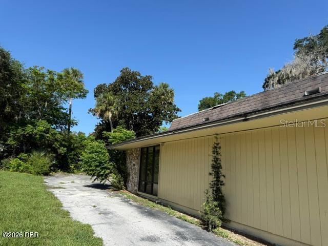 A view of a house exterior with yellow vertical siding and a stone wall — 236 N FREDERICK AVENUE, DAYTONA BEACH, FL