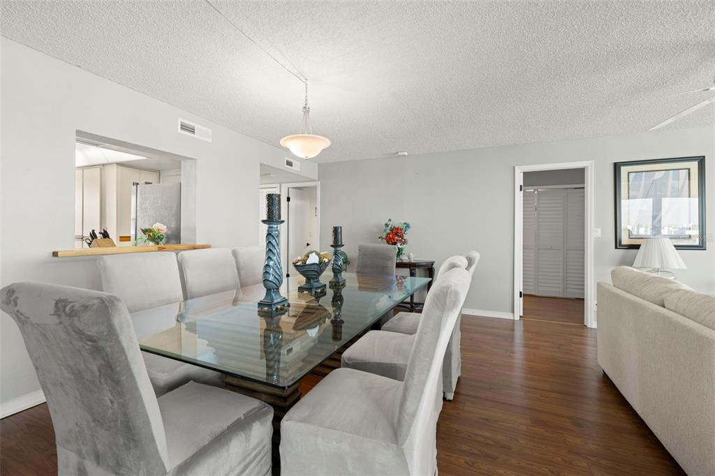 A dining room features a glass-topped table, upholstered chairs, and wood flooring — 9415 BLIND PASS ROAD UNIT 1006, ST PETE BEACH, FL
