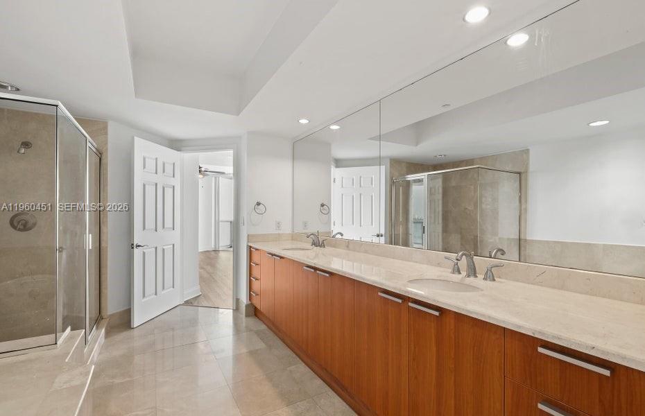 A bathroom features a long wooden double vanity with a stone countertop and large mirror — OTHER CITY - IN THE STATE OF FLORIDA, FL