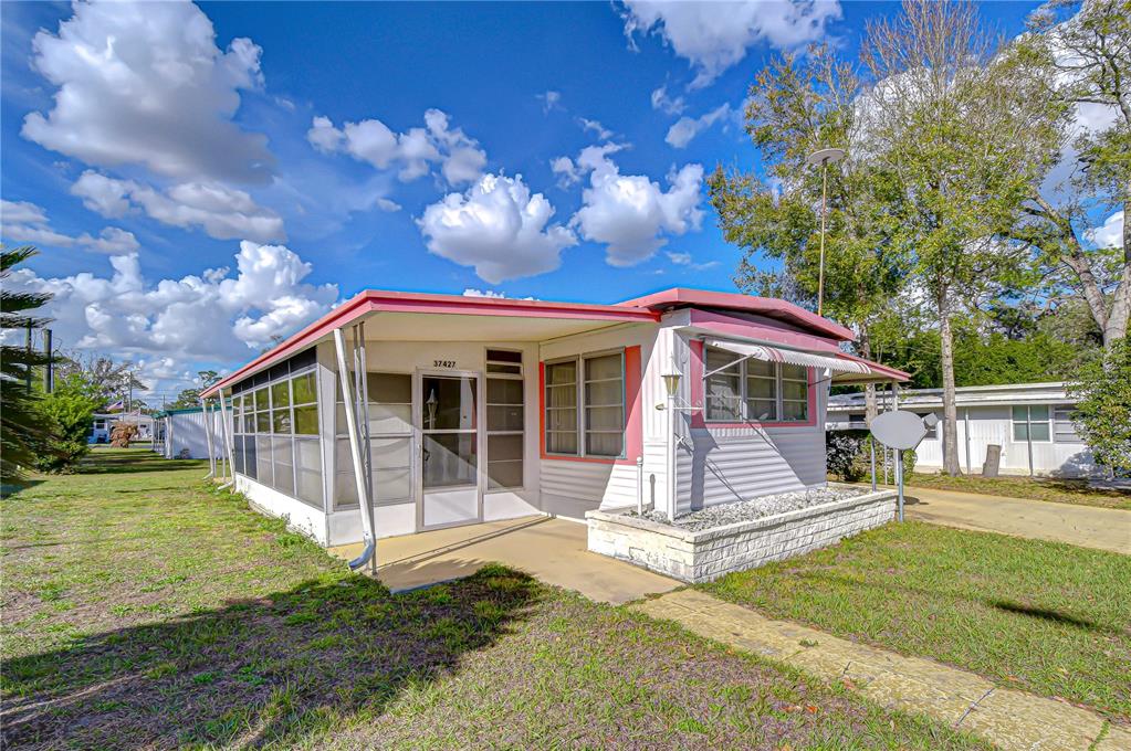 A single-story mobile home features a screened-in porch, white siding, and a concrete walkway — 37427 HAMMOND DRIVE, ZEPHYRHILLS, FL