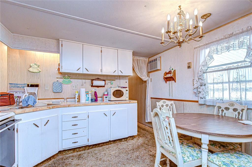 A kitchen with white cabinets, a round dining table, and a chandelier — 37427 HAMMOND DRIVE, ZEPHYRHILLS, FL