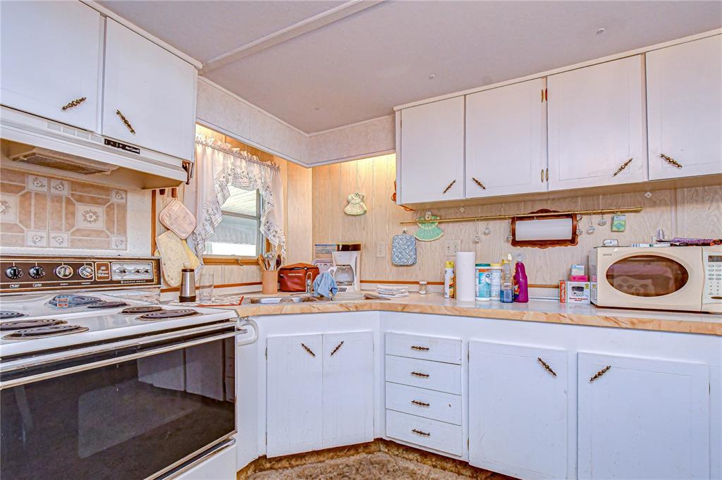 A kitchen with white cabinets, a white electric stove, and a microwave on the counter — 37427 HAMMOND DRIVE, ZEPHYRHILLS, FL