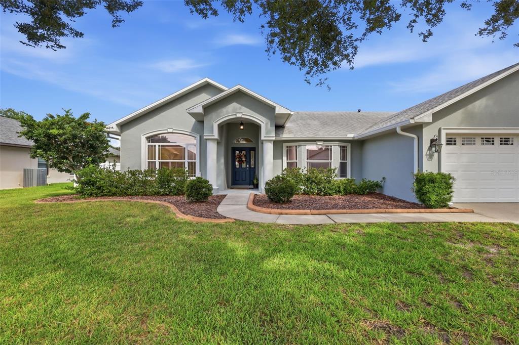 A single-story house with a light gray exterior, arched entryway, and a front-facing garage — 115 RACHEL LIN LANE, ST CLOUD, FL