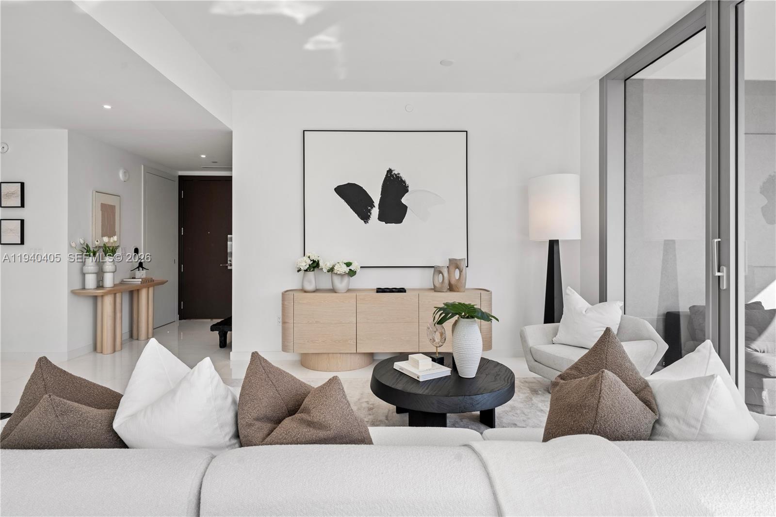 A modern living room features a white sofa, a black coffee table, and a wooden sideboard — 300 Biscayne Blvd Way # 3407, Miami FL 33131, MIAMI, FL