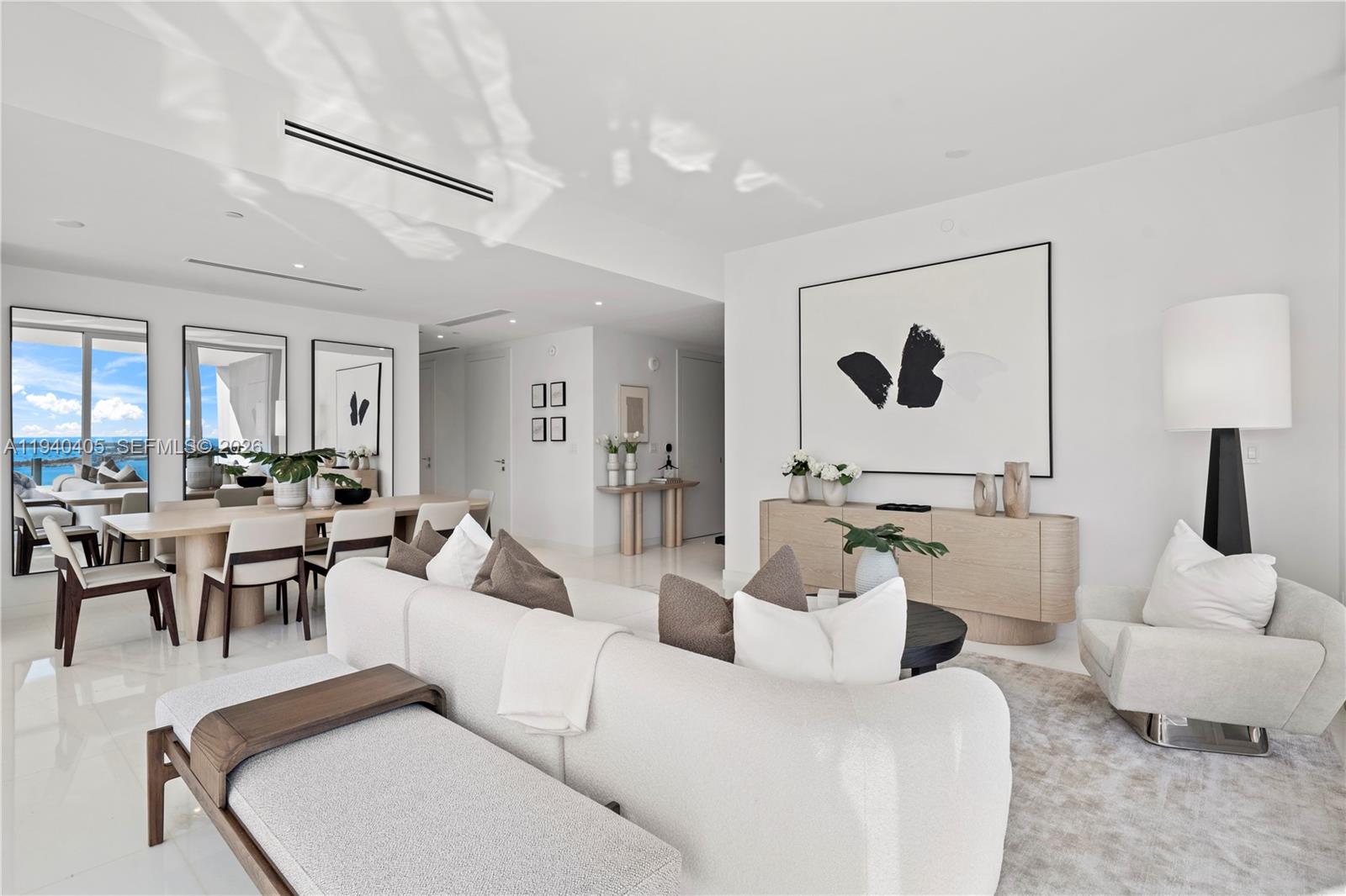 A bright, modern living and dining area features white walls, neutral furniture, and large mirrors — 300 Biscayne Blvd Way # 3407, Miami FL 33131, MIAMI, FL