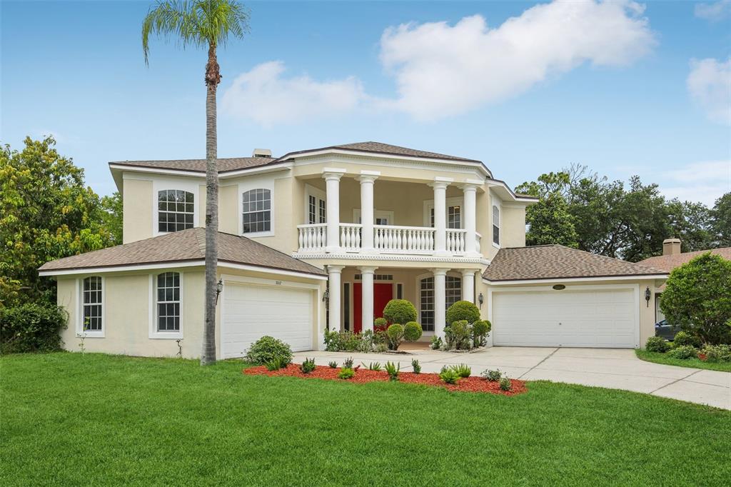 A two-story suburban house with a beige stucco exterior, a columned balcony, and two garages — 3062 SUTTON WOODS DRIVE, PLANT CITY, FL