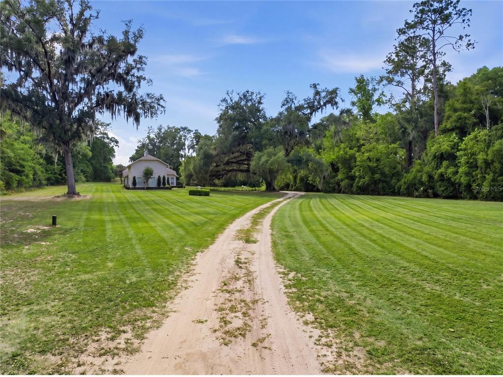 A beige house with a large yard, landscaping, and a blue sky with clouds — 5900 S MAGNOLIA AVENUE, OCALA, FL