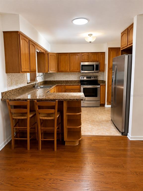 A kitchen with wood cabinets, granite countertops, stainless steel appliances, and a breakfast bar — 11102 28TH STREET, TAMPA, FL