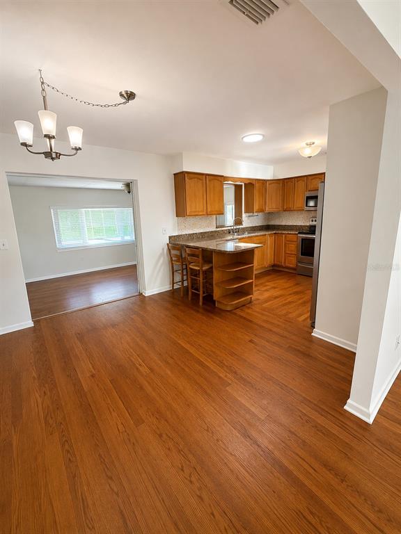 A kitchen with wood cabinets and a breakfast bar opens into a dining area — 11102 28TH STREET, TAMPA, FL