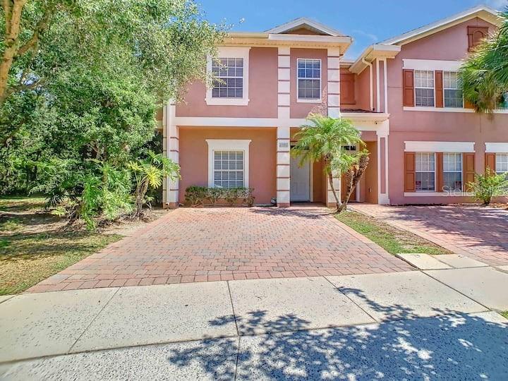 A two-story pink townhouse with a paved driveway and a small front garden — 2356 CARAVELLE CIRCLE, KISSIMMEE, FL