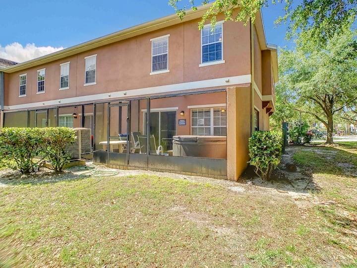 The exterior of a two-story townhouse features a screened-in patio with a hot tub — 2356 CARAVELLE CIRCLE, KISSIMMEE, FL