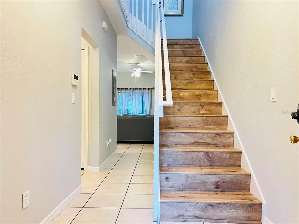 A staircase with wood-look treads and white risers sits beside a tiled entryway — 2356 CARAVELLE CIRCLE, KISSIMMEE, FL