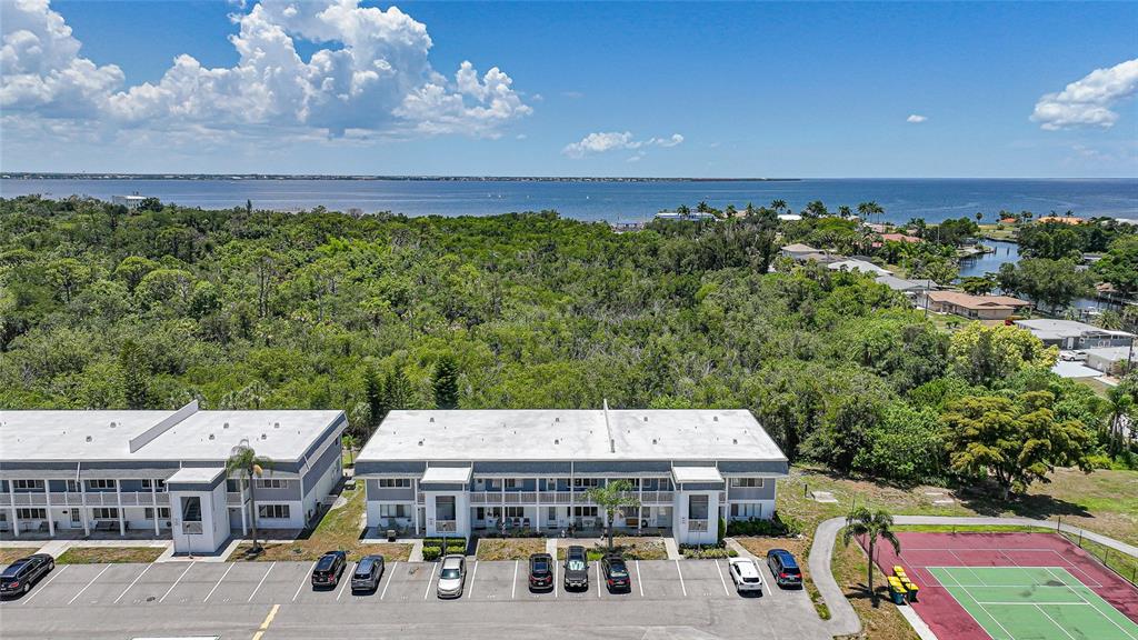 An aerial view shows a multi-story apartment building with a parking lot and tennis court — 22375 EDGEWATER DRIVE UNIT 236, PUNTA GORDA, FL
