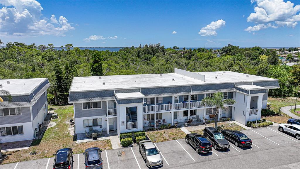 An aerial view shows a two-story apartment building with a parking lot and surrounding trees — 22375 EDGEWATER DRIVE UNIT 236, PUNTA GORDA, FL