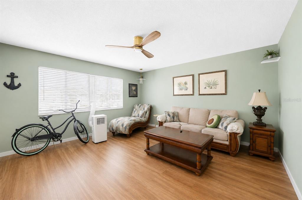 A living room features light green walls, wood-look flooring, a sofa, and a bicycle — 22375 EDGEWATER DRIVE UNIT 236, PUNTA GORDA, FL