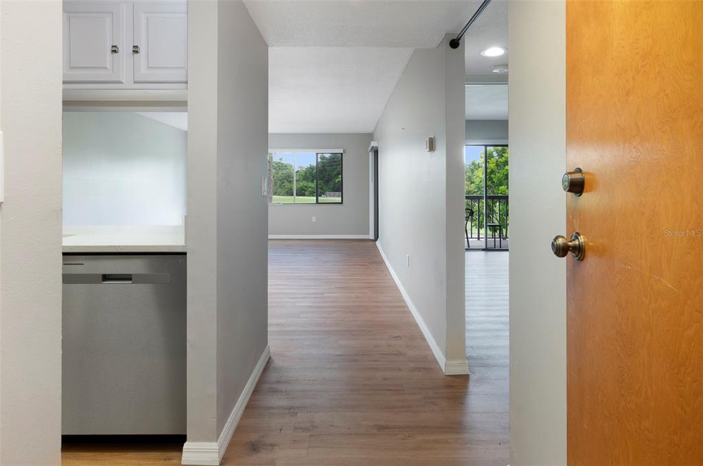 A view from a doorway looking into a kitchen and a living area with flooring — 2593 COUNTRYSIDE BOULEVARD UNIT 7210, CLEARWATER, FL