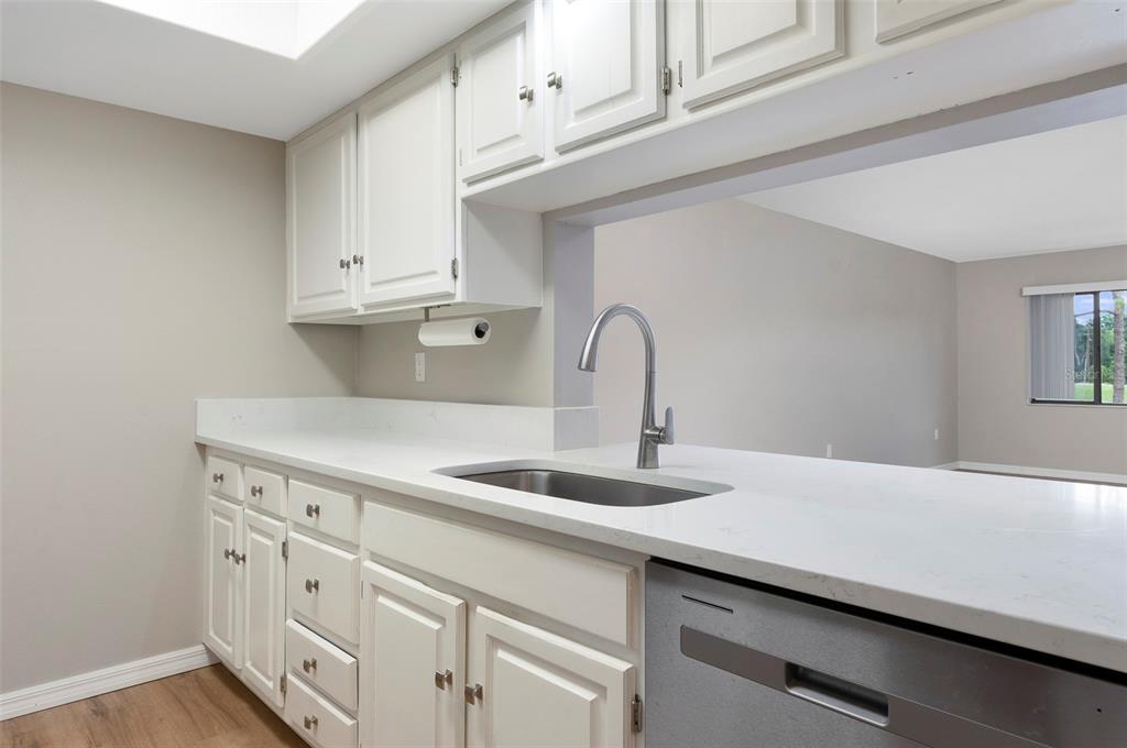 A kitchen features white cabinets, a white countertop, a stainless steel sink, and a dishwasher — 2593 COUNTRYSIDE BOULEVARD UNIT 7210, CLEARWATER, FL