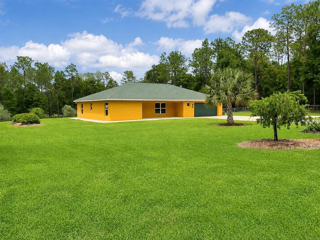 A bright yellow single-story house with a green roof sits on a large grassy lawn — 11931 SW 41ST PLACE, OCALA, FL