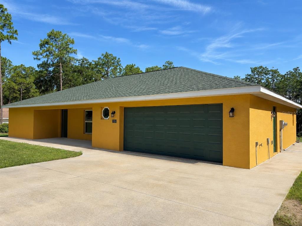 A yellow single-story house with a green garage door and a green shingled roof — 11931 SW 41ST PLACE, OCALA, FL