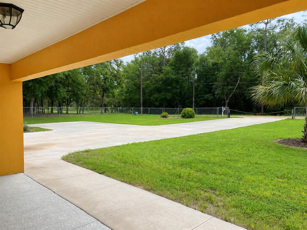A view from a covered porch looking out over a concrete driveway and grassy yard — 11931 SW 41ST PLACE, OCALA, FL