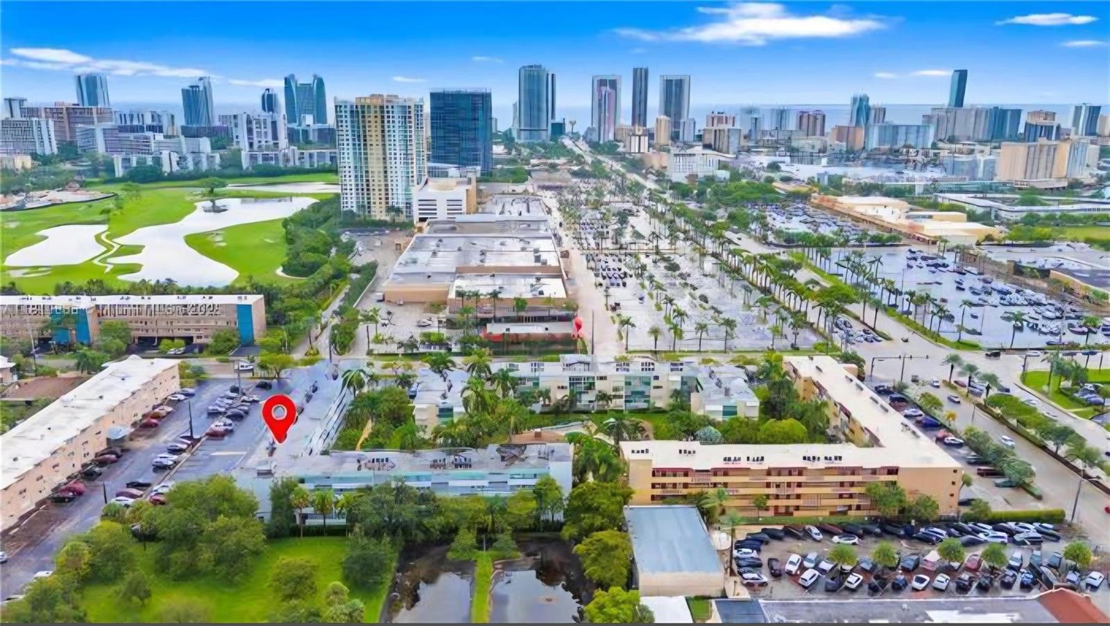 An aerial view of a multi-story apartment complex with a parking lot and surrounding greenery — 1333 E Hallandale Beach Boulevard # 305, Hallandale Beach FL 33009, HALLANDALE BEACH, FL